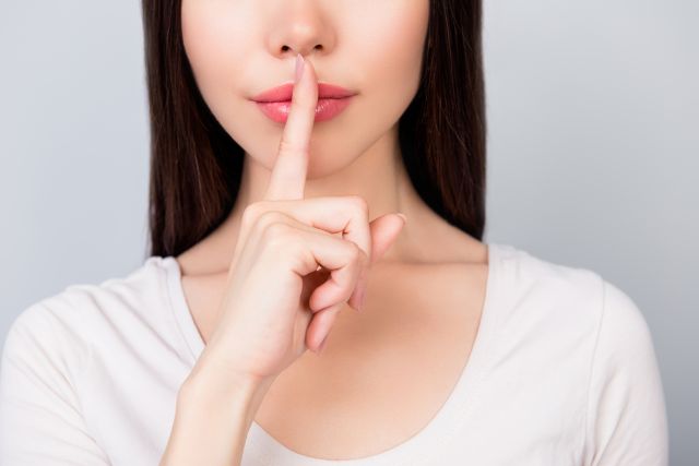 口に人差し指を当てる女性